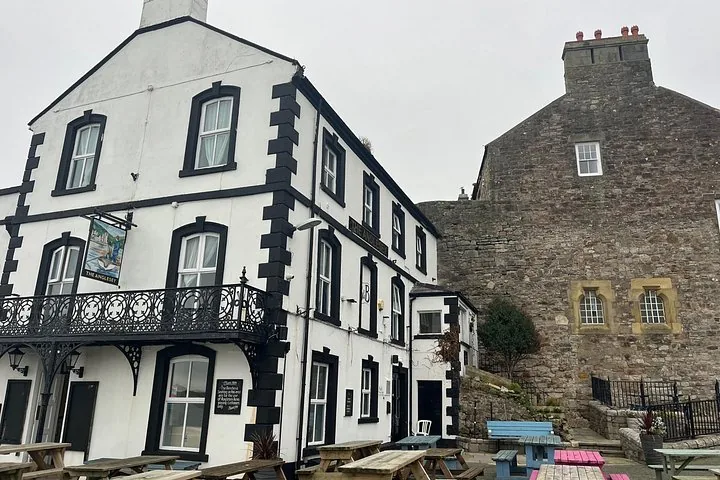 The Anglesey, a white pub with black trim next to stone castle walls