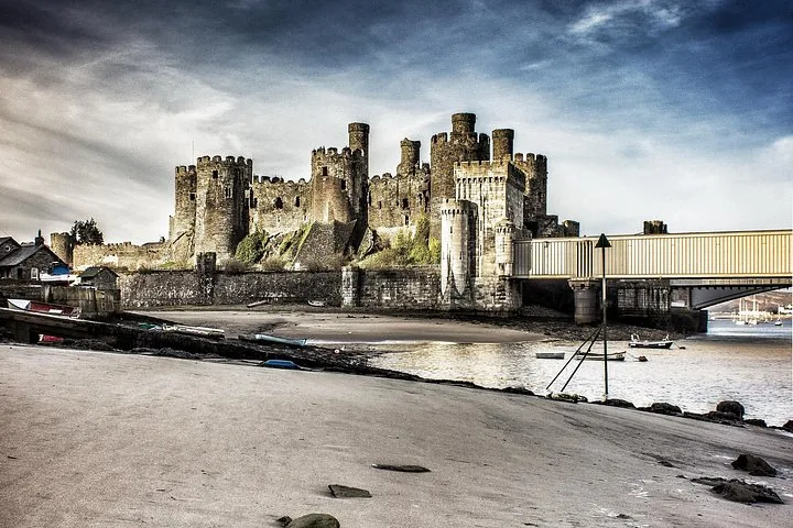 Blick auf Caernarfon Castle und eine Brücke von einem Sandstrand bei Ebbe