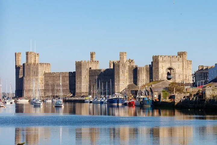 Caernarfon Castle viewed from the water with numerous boats moored in front