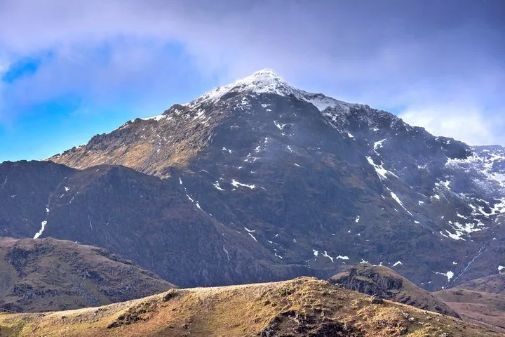Un'alta vetta montuosa con la cima innevata sotto un cielo blu