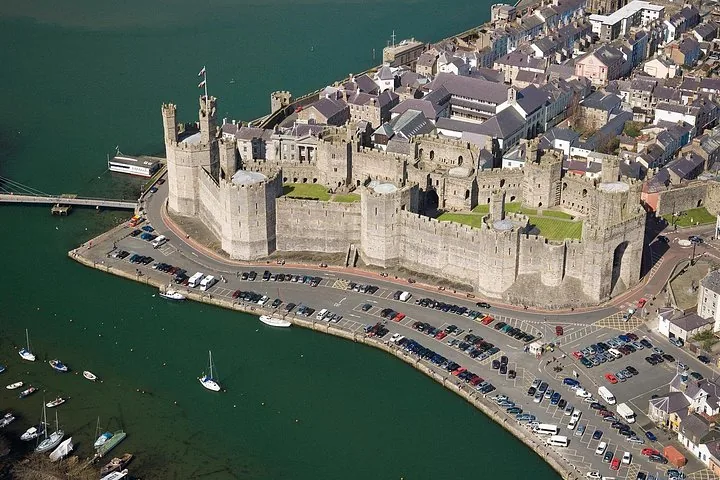 Aerial view of Caernarfon Castle, town, parking lot, and waterfront area